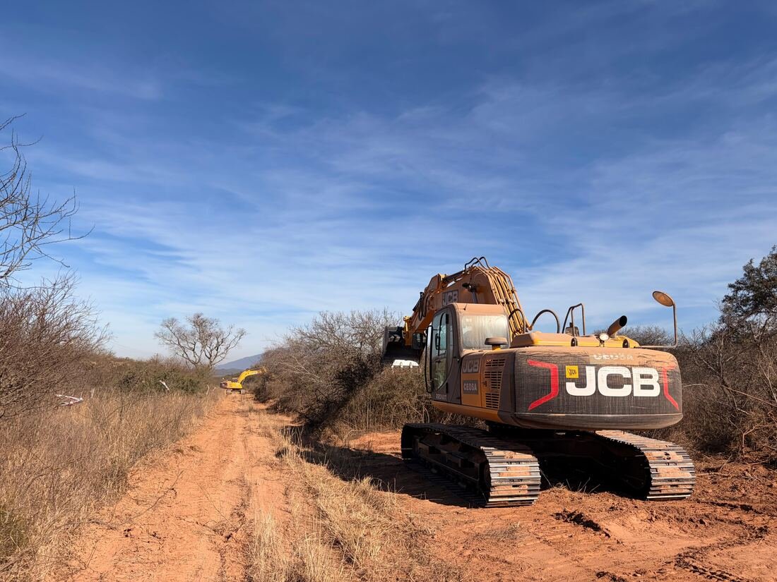 Retroexcavadora JCB CEOSA sobre la traza despejada, con otro equipo trabajando al fondo